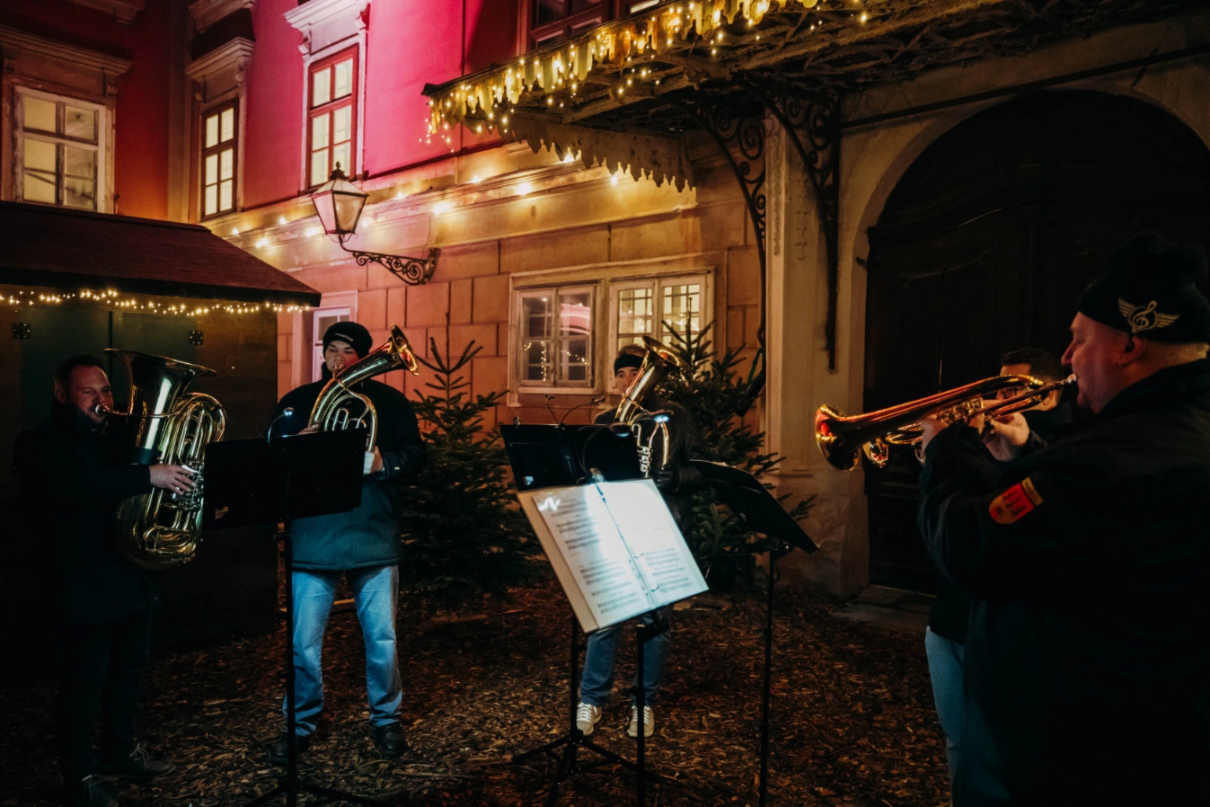 Blasmusikkapelle mit Tuba und Trompete spielt abends vor dem beleuchteten Schloss
